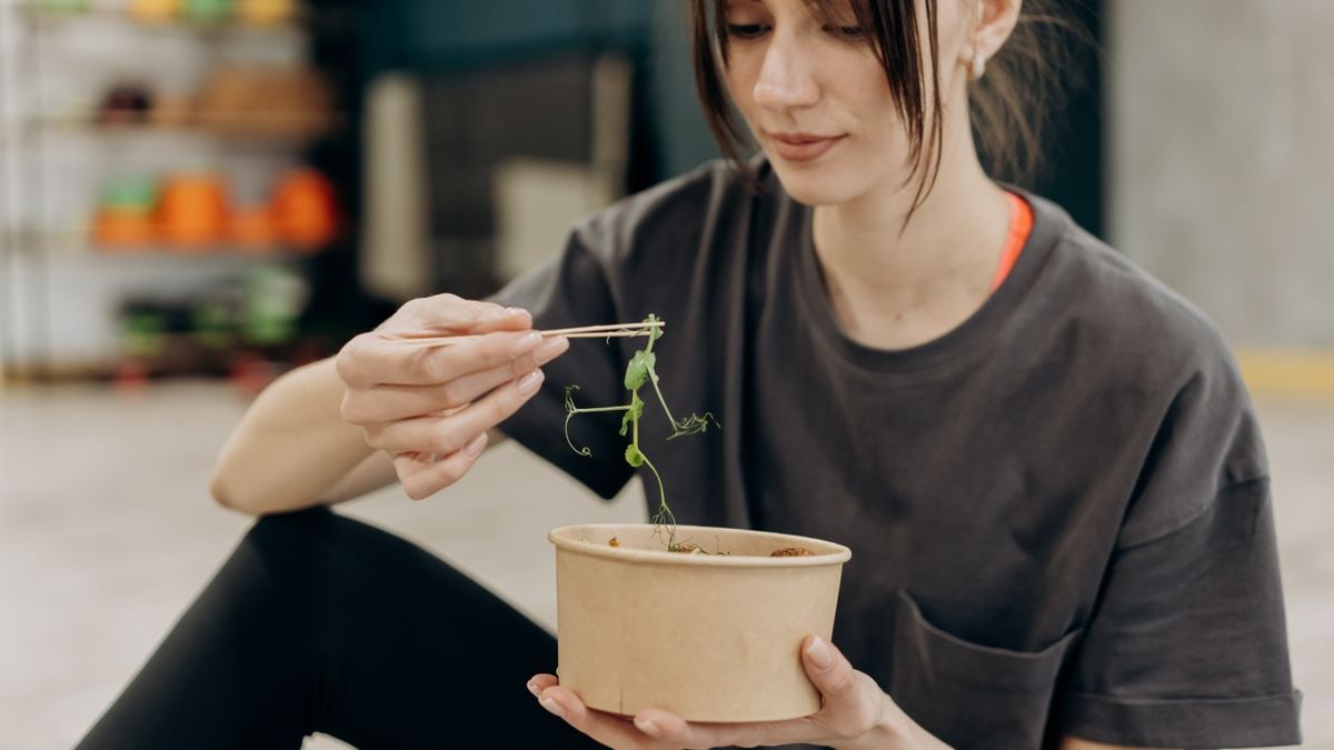 Young woman enjoying a healthy salad indoors, focusing on balanced nutrition and healthy living.